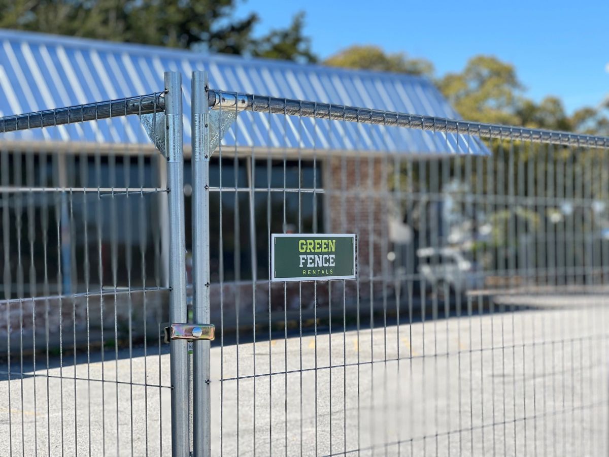 Green Fence Rentals temporary fence panels with company sign installed at a job site